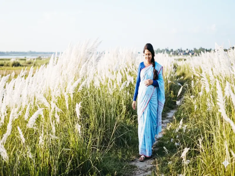 Pregnant woman smiling while checking her blood sugar levels with a digital glucose monitor at home.