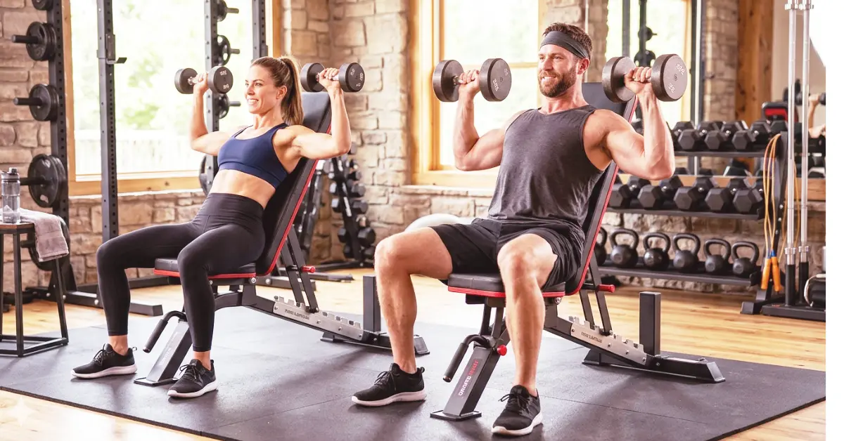 A dynamic photograph of an American man and woman engaged in strength training exercises using black adjustable weight benches in a well-equipped home gym.