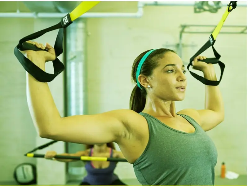 Close-up details of the TRX GO Suspension Trainer straps and comfortable non-slip foam handles anchored firmly for a home physical therapy session.